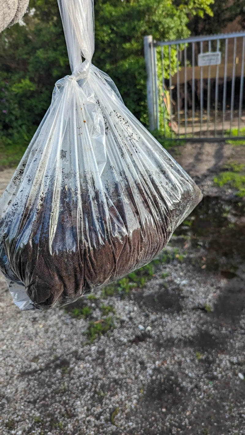Plastic doorzichtige zak gevuld met koffieprut voor compostgebruik