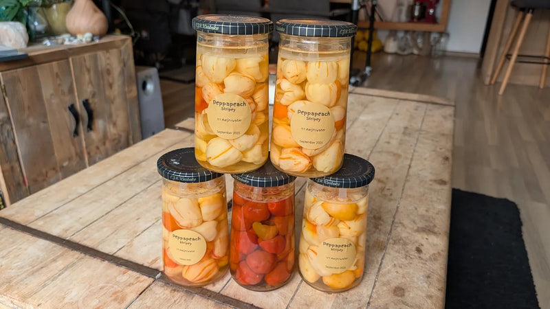 Vier potten met ingemaakte Peppapeach Stripey en één pot met Malawi Peppadew pepers.